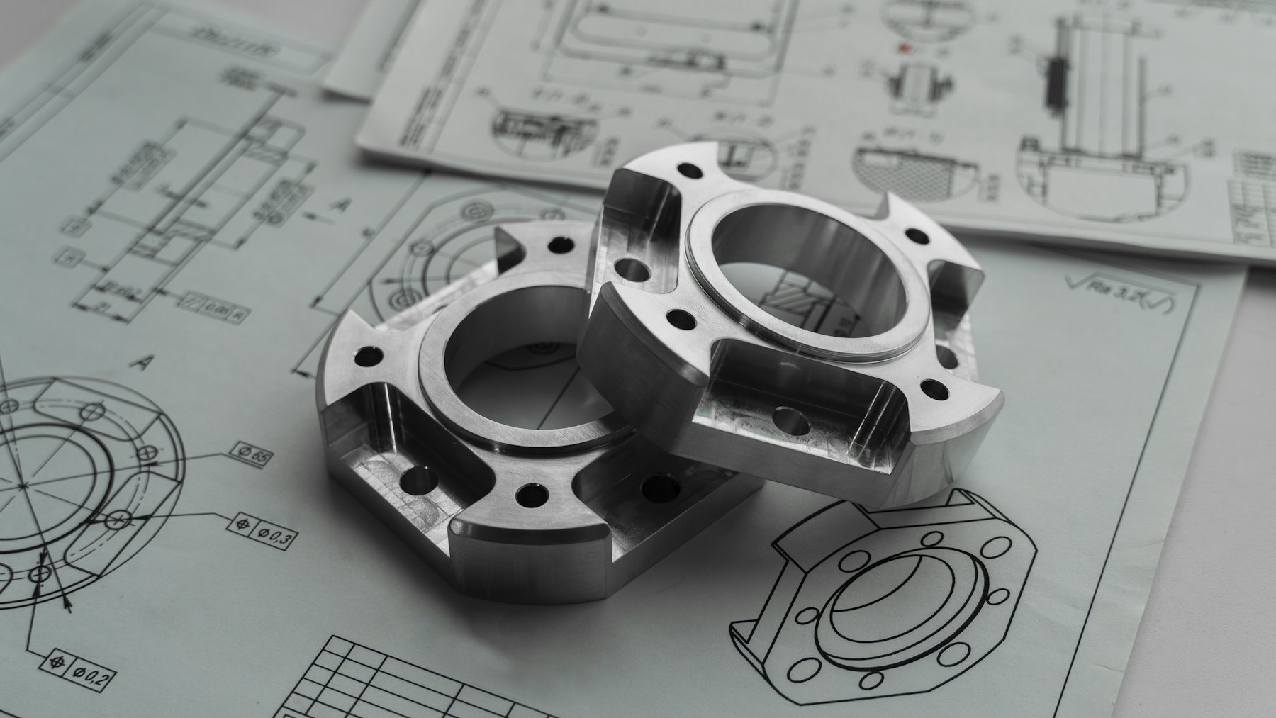 Precision-machined metal components resting on engineering drawings